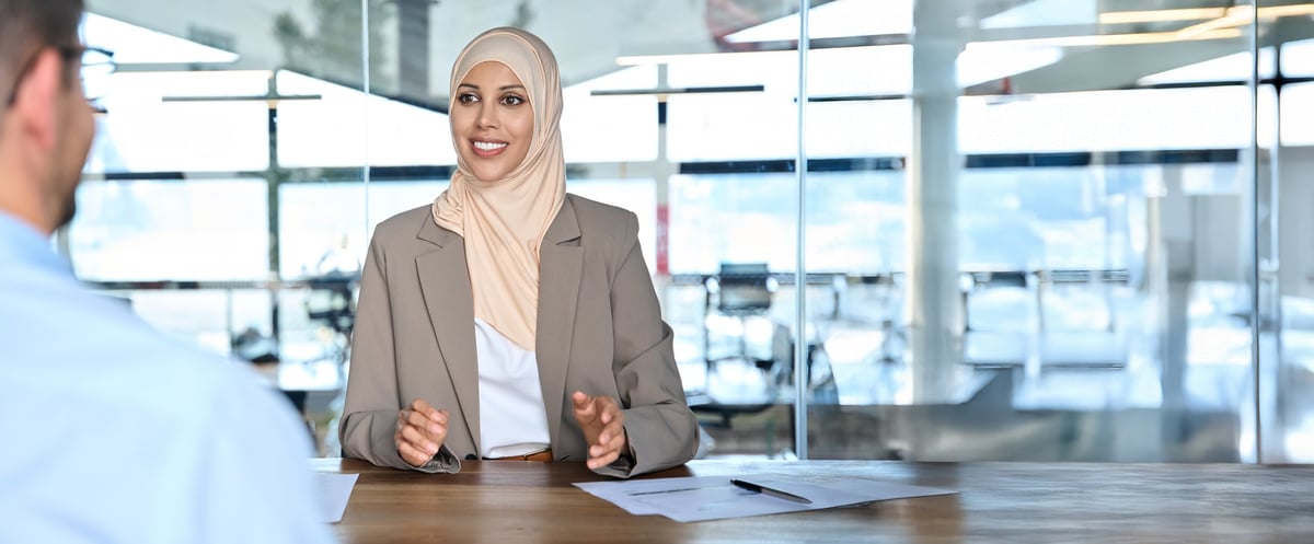 A businesswoman in hijab working with a client in an office