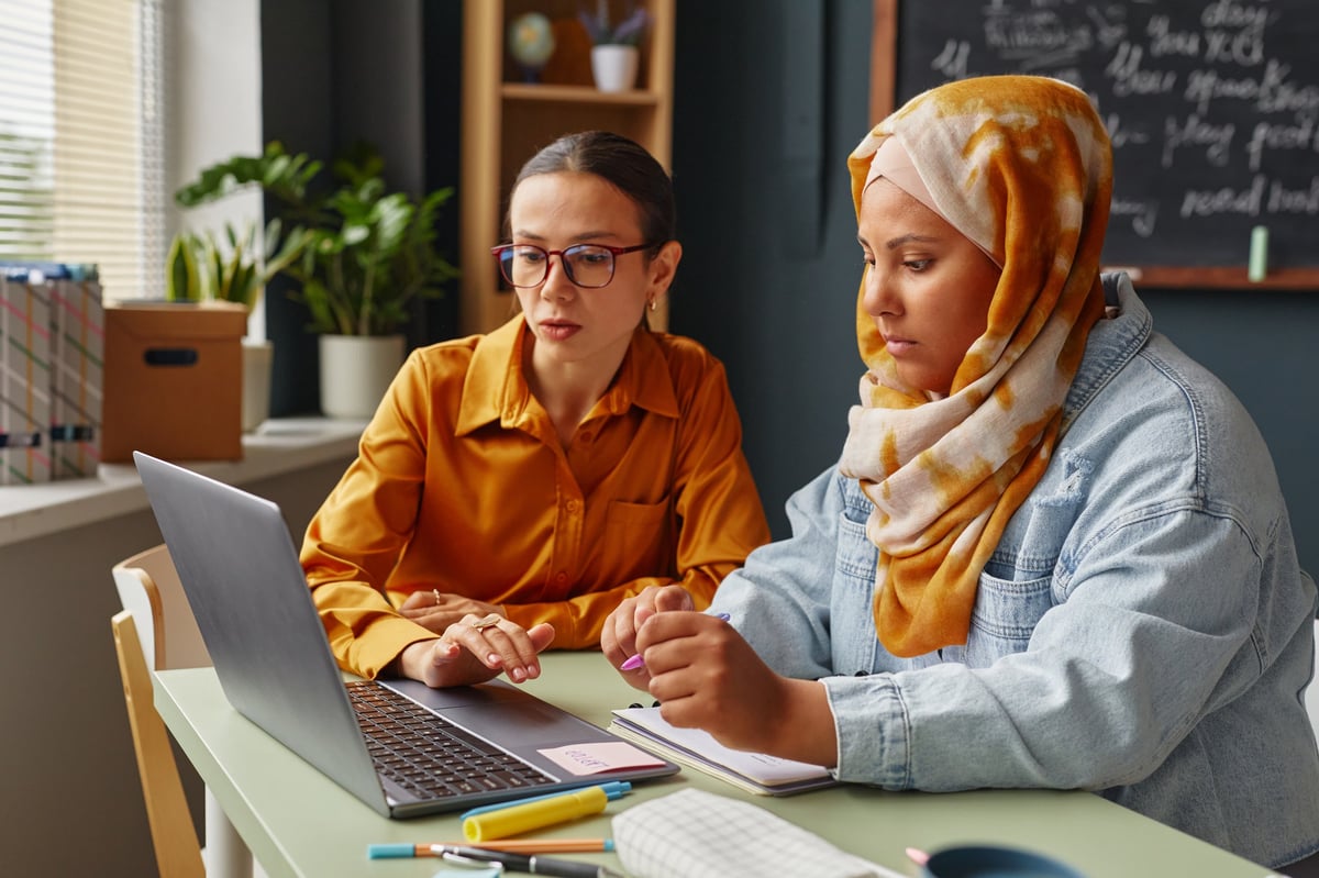 Two women in hijab studying together at a language school